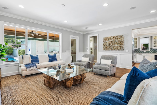 living room featuring ornamental molding, wood-type flooring, and ceiling fan