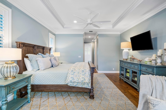 bedroom with ceiling fan, dark hardwood / wood-style flooring, a tray ceiling, and ornamental molding