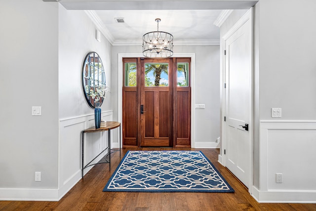 foyer entrance featuring dark hardwood / wood-style flooring, a notable chandelier, and ornamental molding