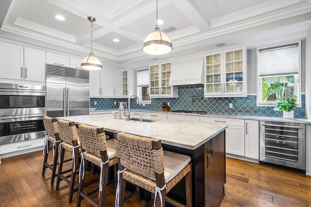 kitchen featuring beverage cooler, dark hardwood / wood-style flooring, stainless steel appliances, a center island with sink, and custom range hood