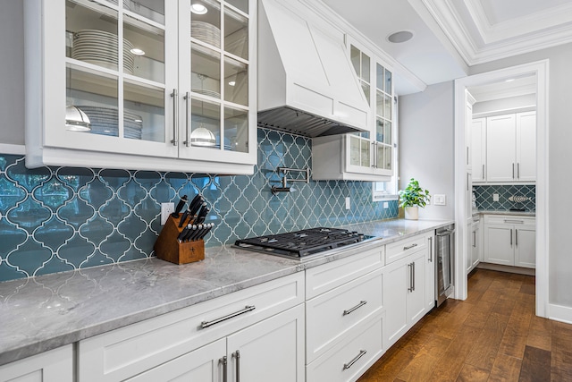 kitchen with custom range hood, tasteful backsplash, dark wood-type flooring, light stone counters, and white cabinets