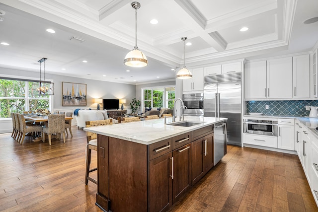 kitchen featuring tasteful backsplash, dark wood-type flooring, appliances with stainless steel finishes, beam ceiling, and coffered ceiling