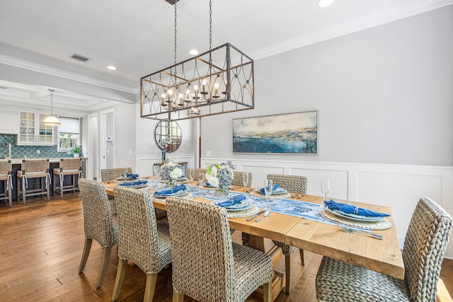 dining area featuring a notable chandelier, hardwood / wood-style flooring, and ornamental molding