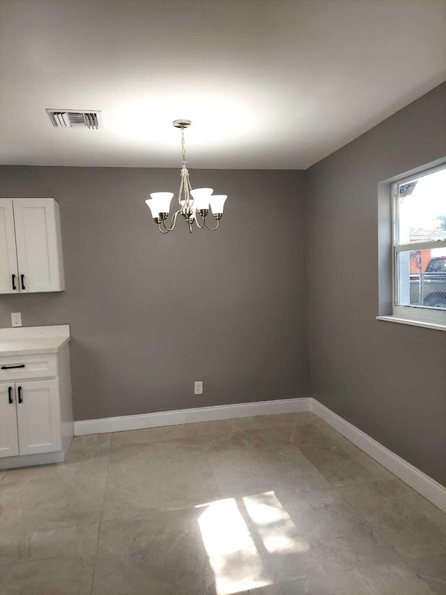 tiled spare room with a chandelier