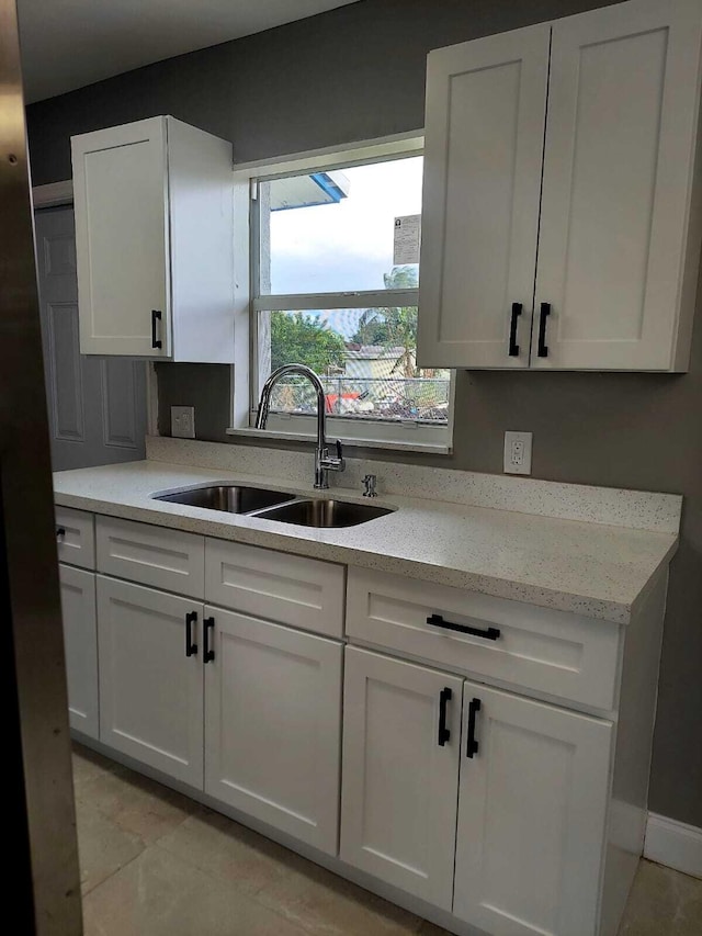 kitchen with white cabinets, sink, and light tile floors