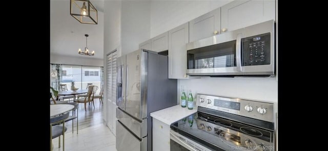 kitchen with appliances with stainless steel finishes, a chandelier, decorative light fixtures, and light tile patterned floors