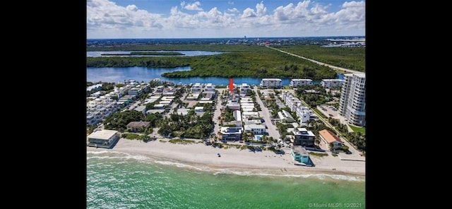 birds eye view of property with a water view and a beach view