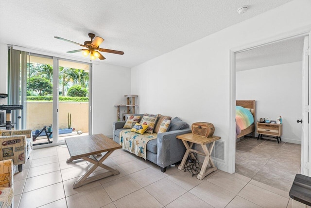 living room featuring expansive windows, light tile patterned flooring, and a textured ceiling