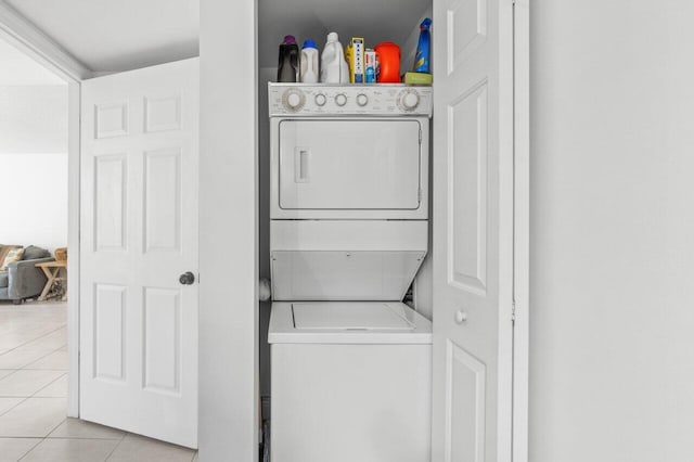 laundry area featuring stacked washer and dryer and light tile patterned flooring