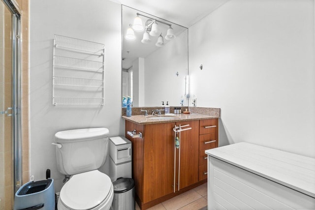 bathroom with tile patterned flooring, vanity, a shower with shower door, and toilet