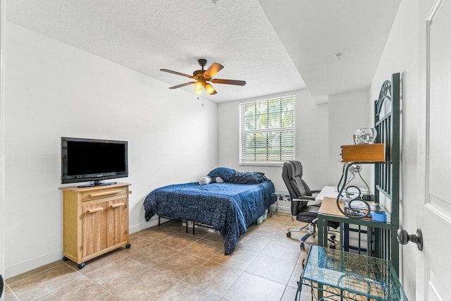 bedroom featuring ceiling fan, light tile patterned floors, and a textured ceiling