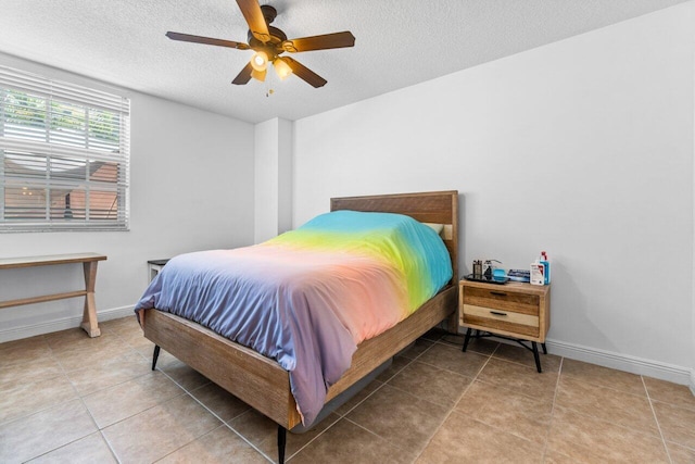 tiled bedroom with ceiling fan and a textured ceiling