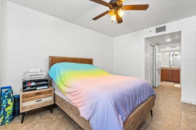 tiled bedroom with ceiling fan, connected bathroom, and a textured ceiling