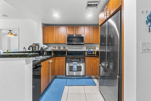 kitchen with light tile patterned flooring, sink, dark stone countertops, appliances with stainless steel finishes, and ceiling fan