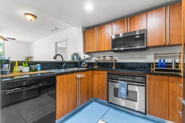 kitchen with sink, ceiling fan, appliances with stainless steel finishes, dark stone countertops, and a textured ceiling