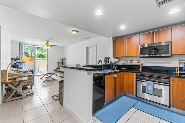 kitchen with dark stone countertops, sink, light tile patterned floors, and stainless steel appliances