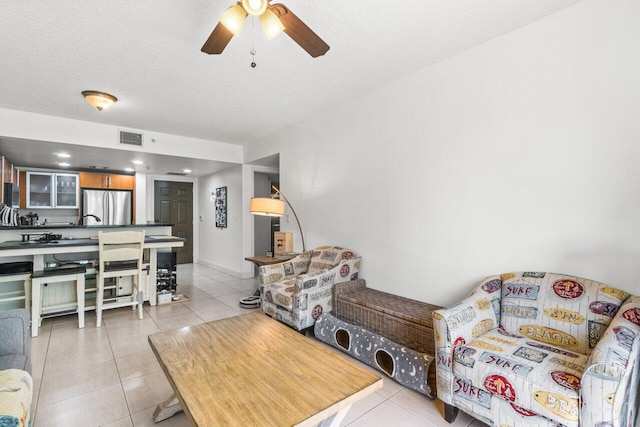 living room with light tile patterned flooring, ceiling fan, and a textured ceiling