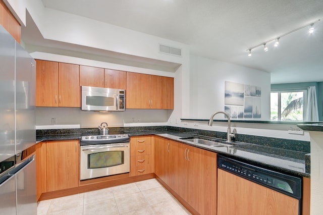 kitchen with dark stone countertops, light tile patterned flooring, appliances with stainless steel finishes, and sink