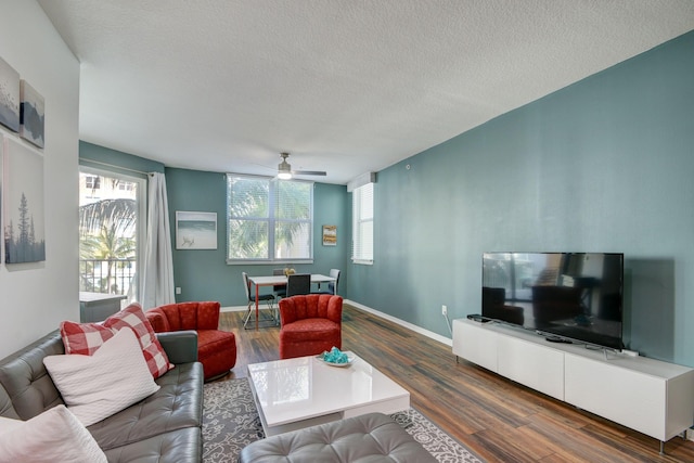 living room with baseboards, wood finished floors, a ceiling fan, and a textured ceiling