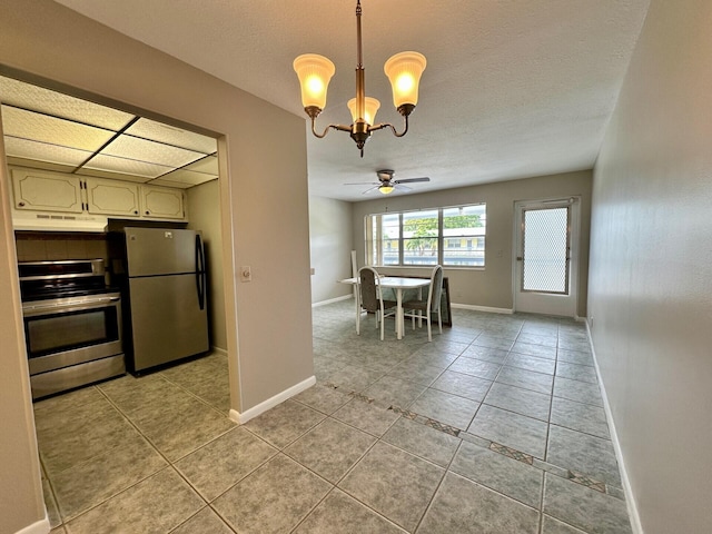 kitchen featuring ceiling fan with notable chandelier, range, stainless steel refrigerator, pendant lighting, and light tile floors