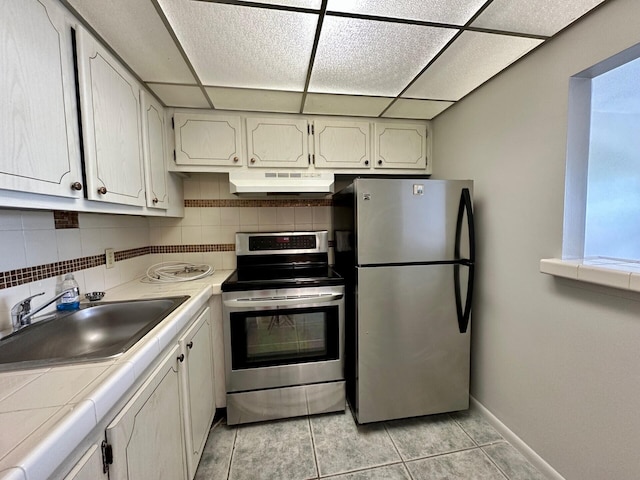 kitchen featuring exhaust hood, appliances with stainless steel finishes, backsplash, light tile flooring, and sink