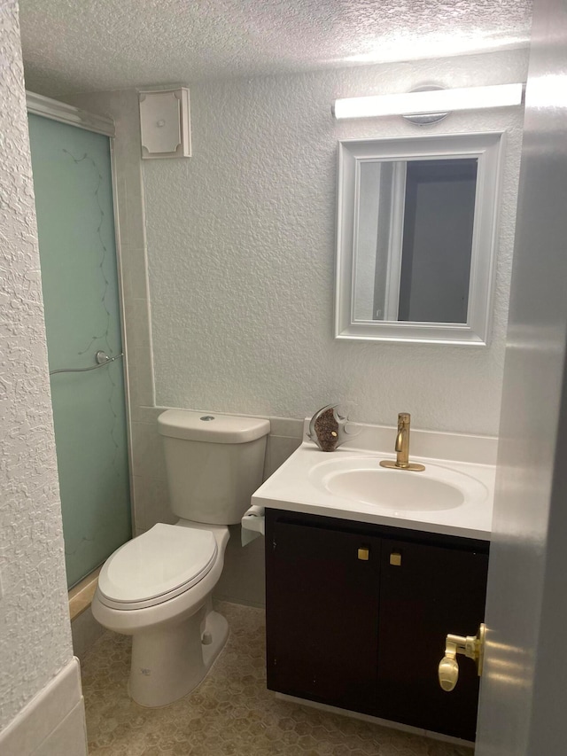 bathroom featuring a textured ceiling, vanity, toilet, and tile flooring