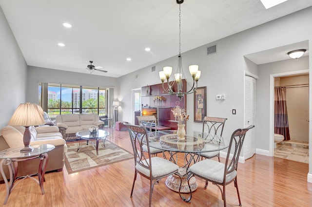 dining space featuring ceiling fan with notable chandelier and wood-type flooring