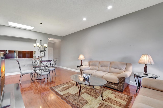 living room featuring an inviting chandelier, a textured ceiling, hardwood / wood-style flooring, and a skylight