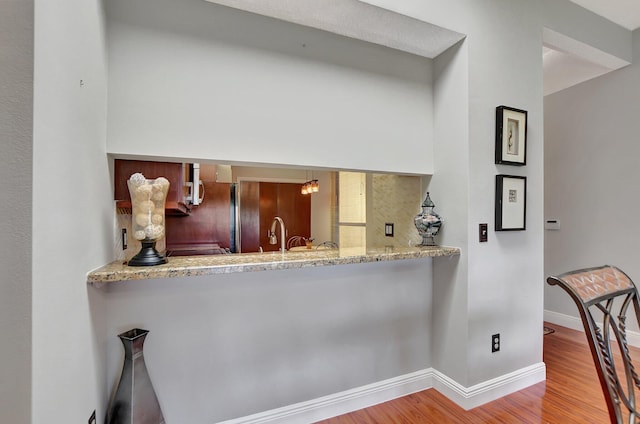 kitchen featuring kitchen peninsula, light hardwood / wood-style flooring, and light stone counters