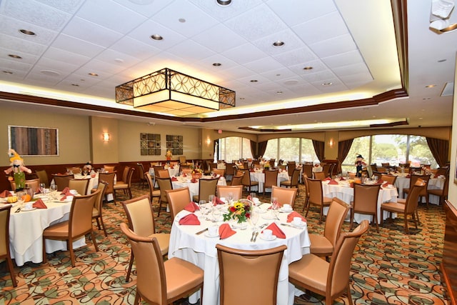 dining space featuring a drop ceiling, carpet flooring, and a tray ceiling