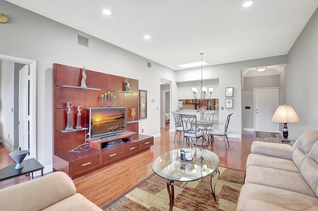 living room with light hardwood / wood-style flooring and an inviting chandelier