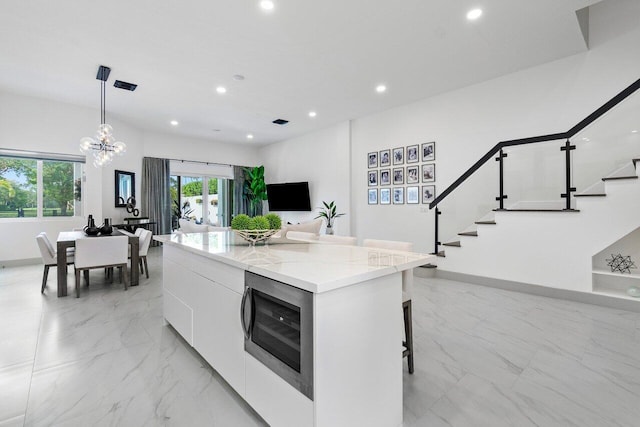 kitchen with sink, wall chimney exhaust hood, a center island, stainless steel appliances, and a breakfast bar