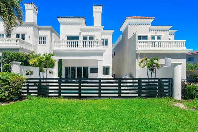 rear view of house featuring a balcony and a yard