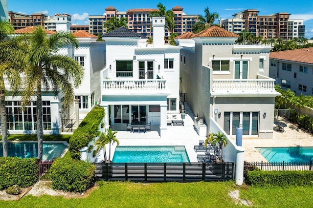 rear view of property featuring a balcony, a patio, and a fenced in pool