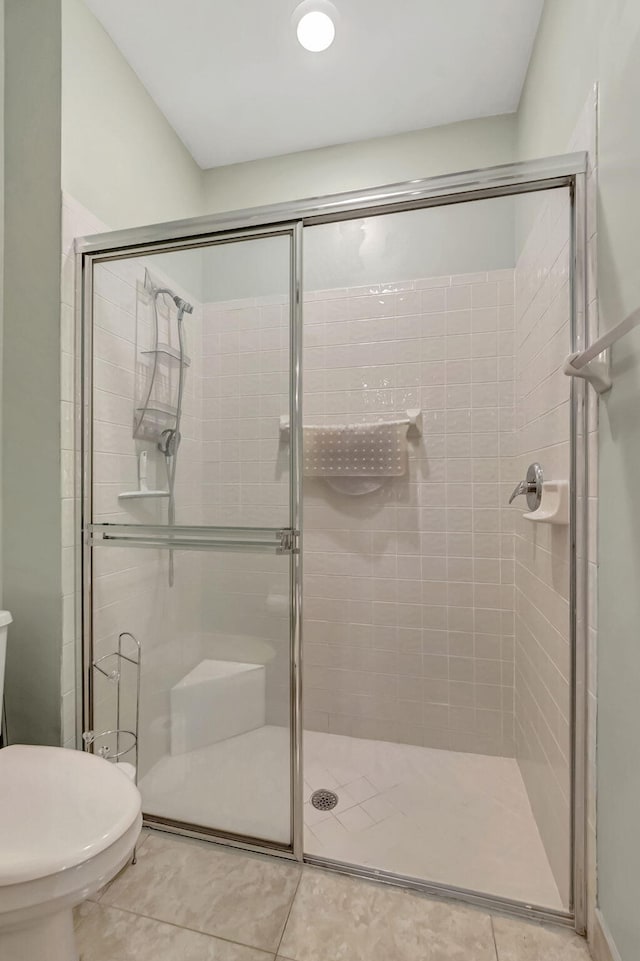 bathroom with a shower with shower door, tile floors, and toilet