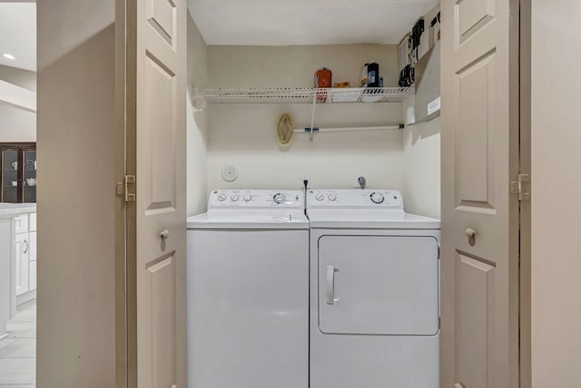 washroom with washing machine and clothes dryer and light tile flooring