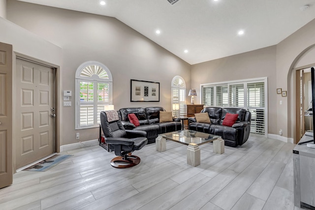 living room with high vaulted ceiling and light wood-type flooring