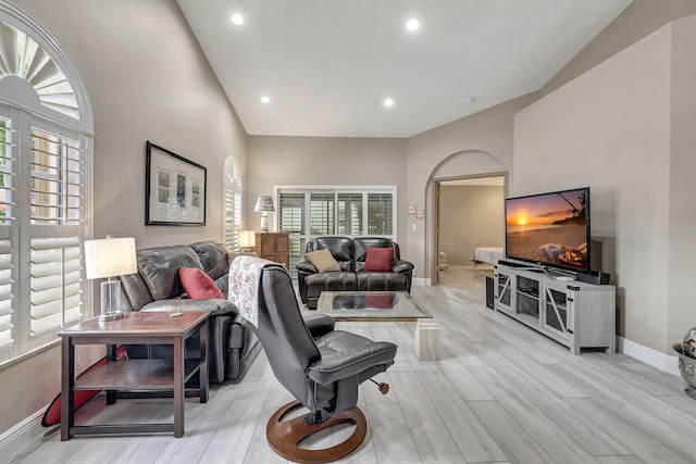 living room with a wealth of natural light, light hardwood / wood-style floors, and lofted ceiling