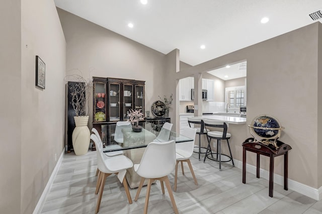 tiled dining room featuring lofted ceiling and sink