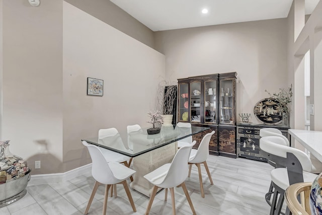 dining space featuring light tile floors and a high ceiling