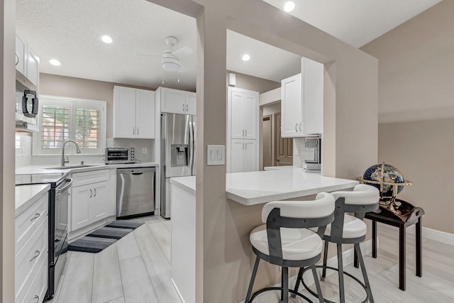 kitchen featuring appliances with stainless steel finishes, white cabinetry, sink, and light wood-type flooring