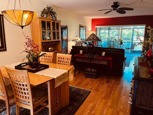 dining space featuring wood-type flooring, a textured ceiling, and ceiling fan