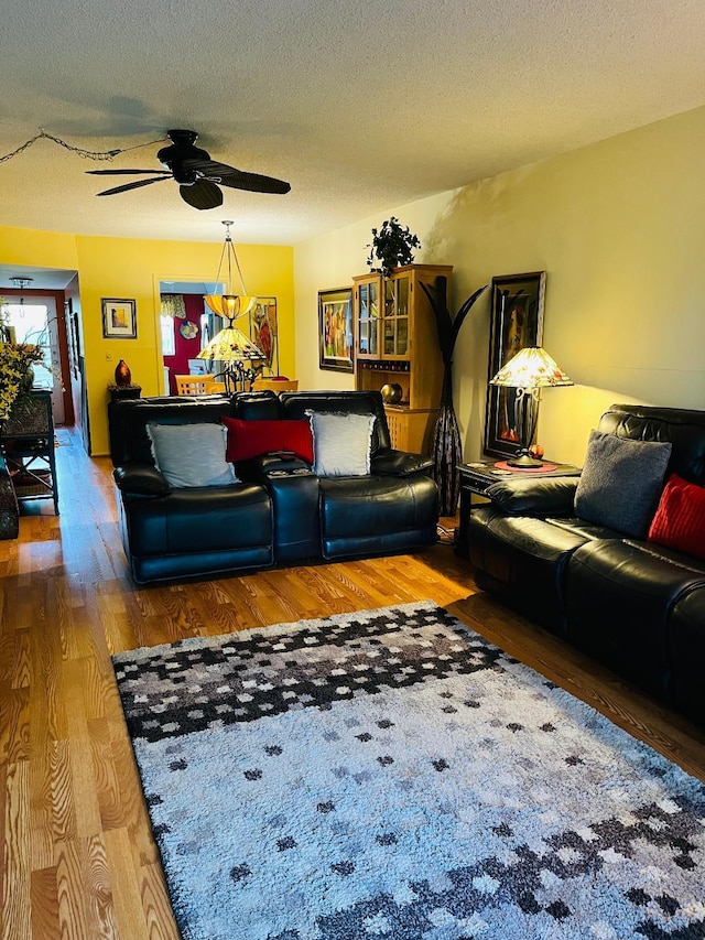 living room with hardwood / wood-style flooring, ceiling fan, and a textured ceiling