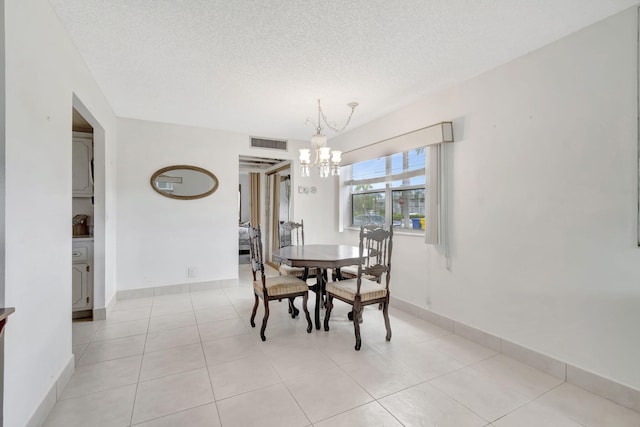 tiled dining space with a chandelier and a textured ceiling