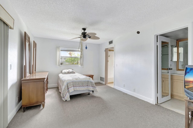 carpeted bedroom featuring ensuite bath, ceiling fan, and a textured ceiling