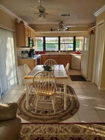 tiled dining area featuring crown molding and ceiling fan