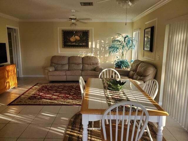 tiled living room featuring ornamental molding and ceiling fan