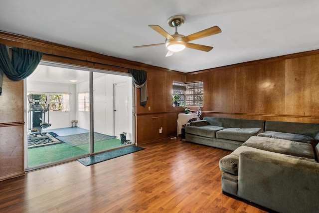 living room featuring wooden walls, hardwood / wood-style floors, and ceiling fan