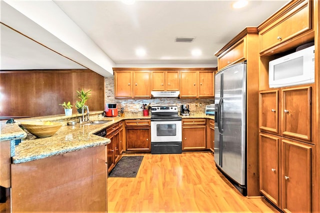 kitchen featuring backsplash, stainless steel appliances, light hardwood / wood-style floors, light stone countertops, and sink