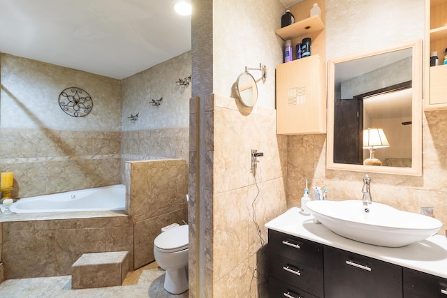 bathroom with vanity, tile walls, tiled tub, toilet, and tile patterned flooring